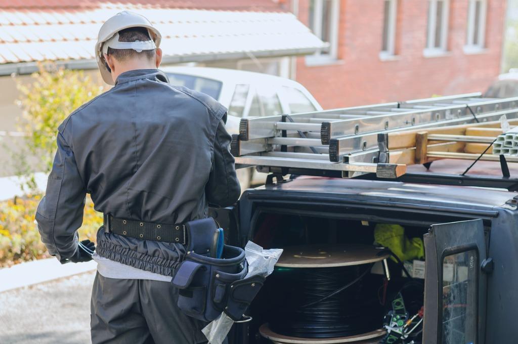 Engineer standing at the back of a van with tools and data equipment, illustrating preparedness and mobility for on-site network installation, VoIP business and maintenance."