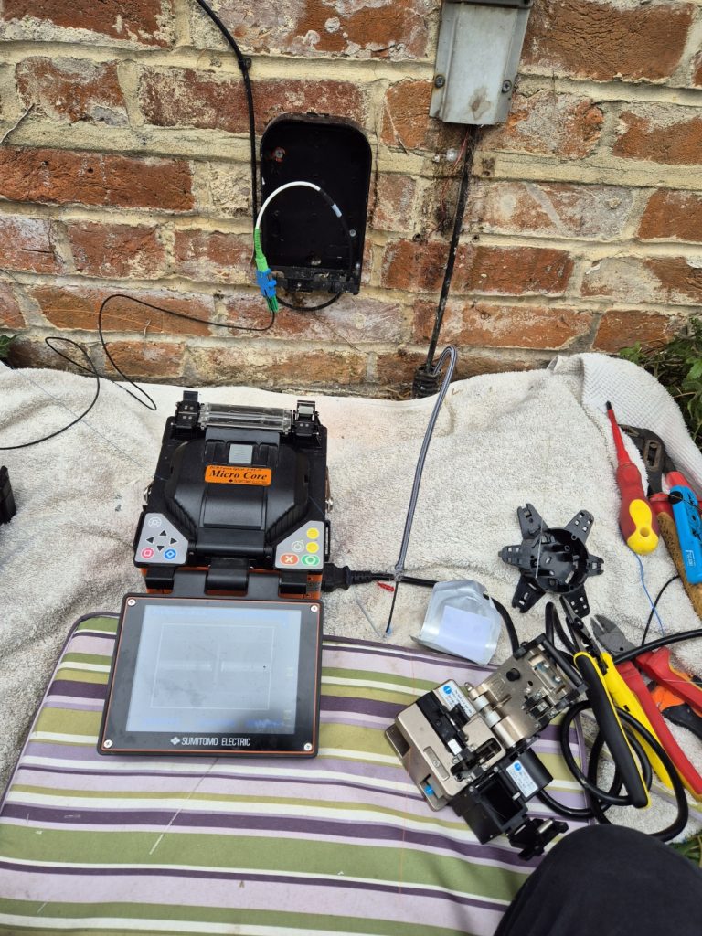 Technician performing fibre splicing to repair a damaged fibre optic cable using a fibre splicer, ensuring seamless connectivity and restoring high-speed internet service.